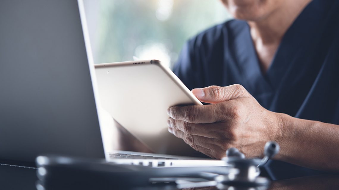 Image of a doctor using a laptop and mobile device